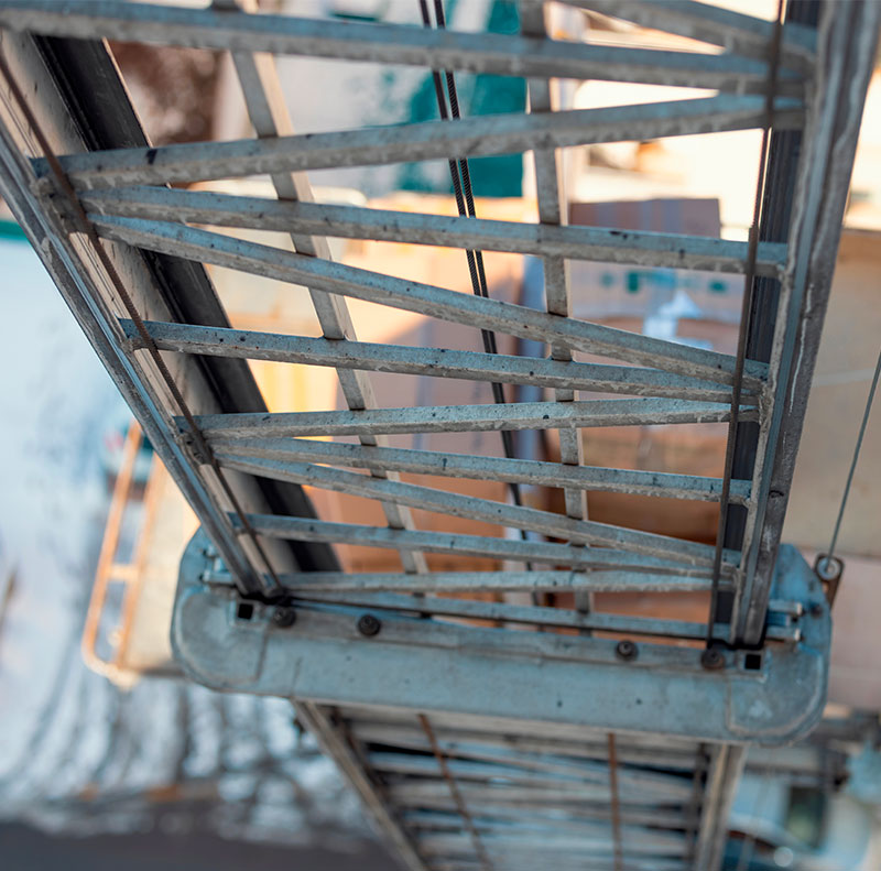 Primo piano sulla robusta struttura metallica e sui binari di scorrimento di un elevatore professionale (autoscala) per traslochi ai piani alti