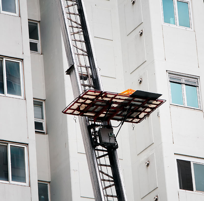 Primo piano sulla piattaforma di un elevatore esterno (autoscala) posizionata all'altezza di una finestra di un palazzo per traslochi ai piani alti